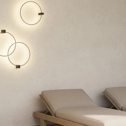 Zandgrijze wand met ronde wandlampen boven ligbedden