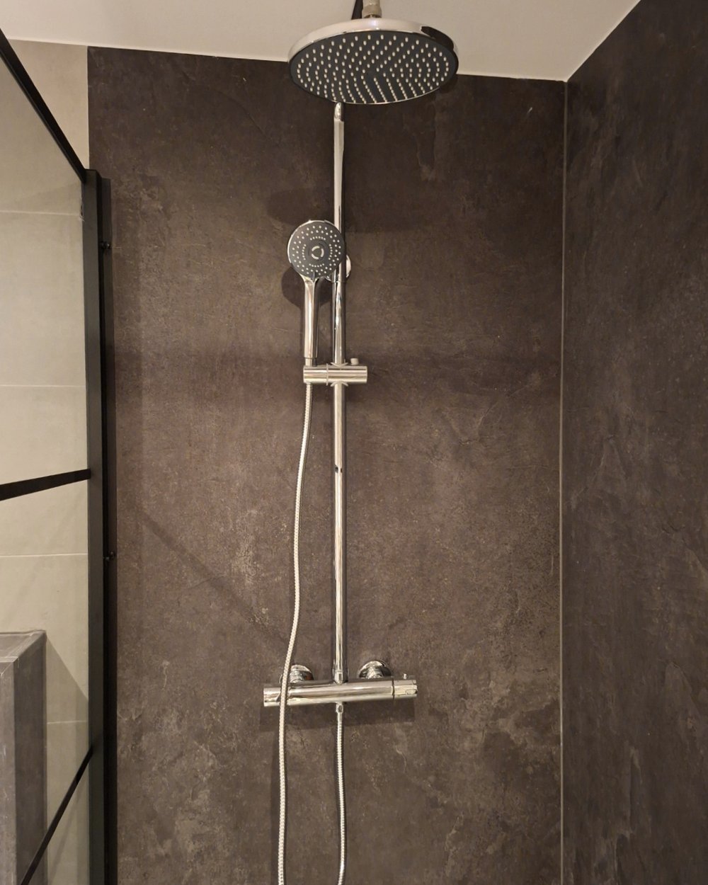 Douche wandpanelen in zwarte kalksteenlook rond een regendouche