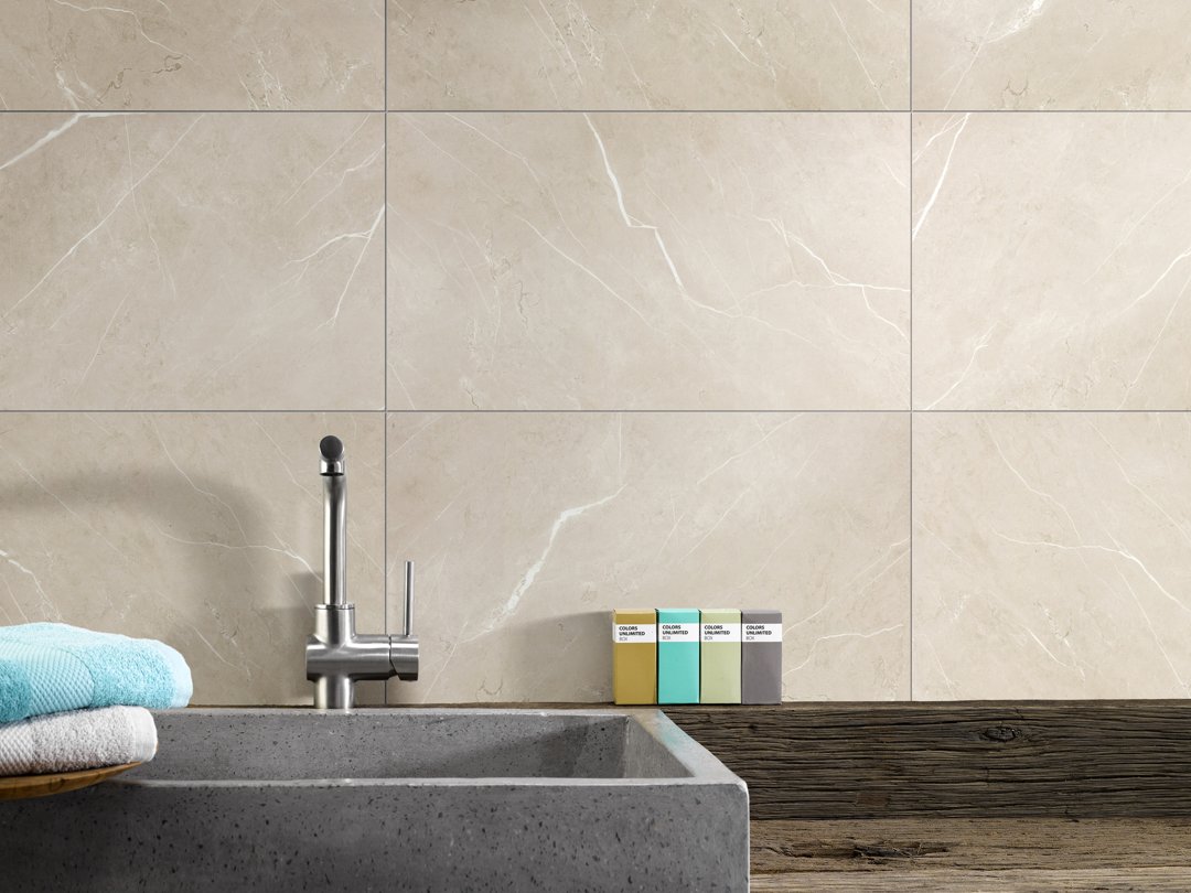 Muurbekleding binnen: beige marmerlook tegelpanelen achter een stenen wastafel