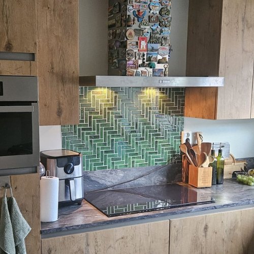 Groene visgraat plaktegels tussen de keukenkastjes