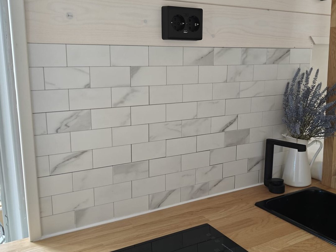 Klantfoto van witte marmerlook plaktegels op een wc muur