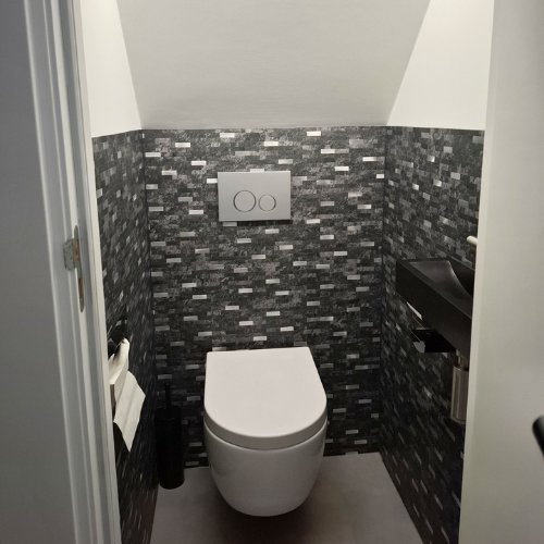 Toilet met donkergrijze steenstrip plaktegels rondom